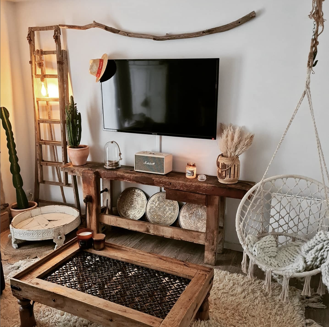 Sala boho com madeira rústica, cadeira suspensa e luz acolhedora
